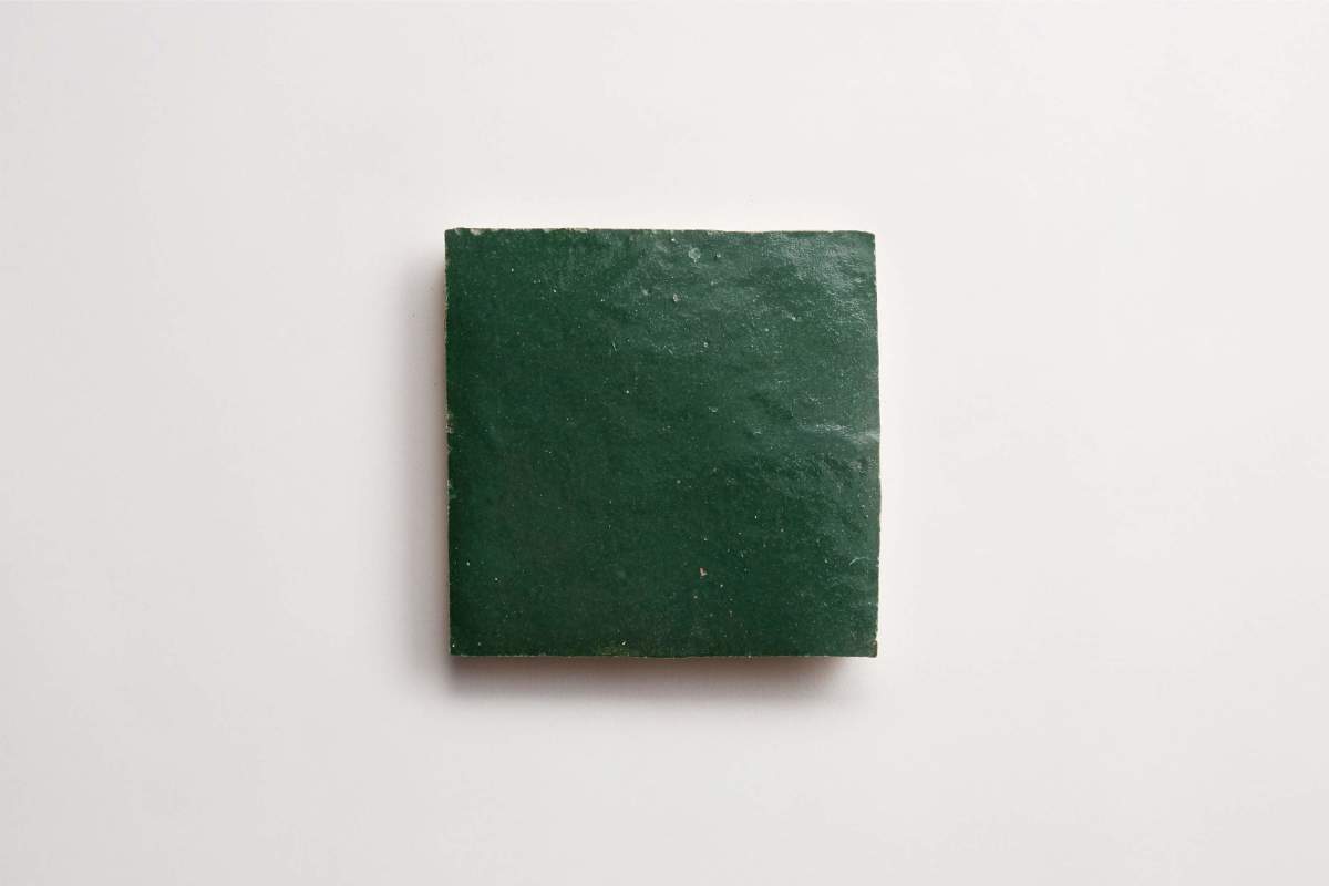 A single square dark green tile placed on a plain white background.