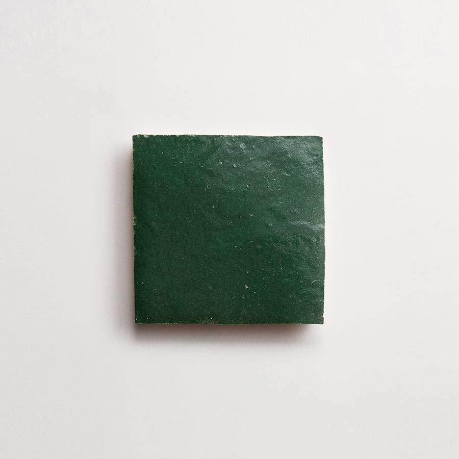 A single dark green square tile is centered on a plain white background.