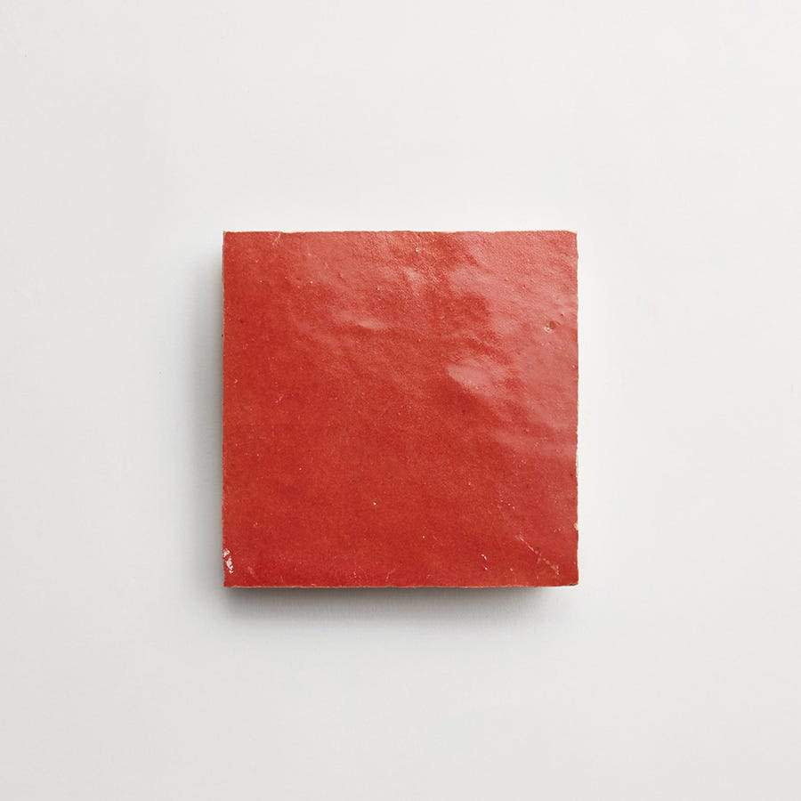 A single square red ceramic tile placed on a plain white background.