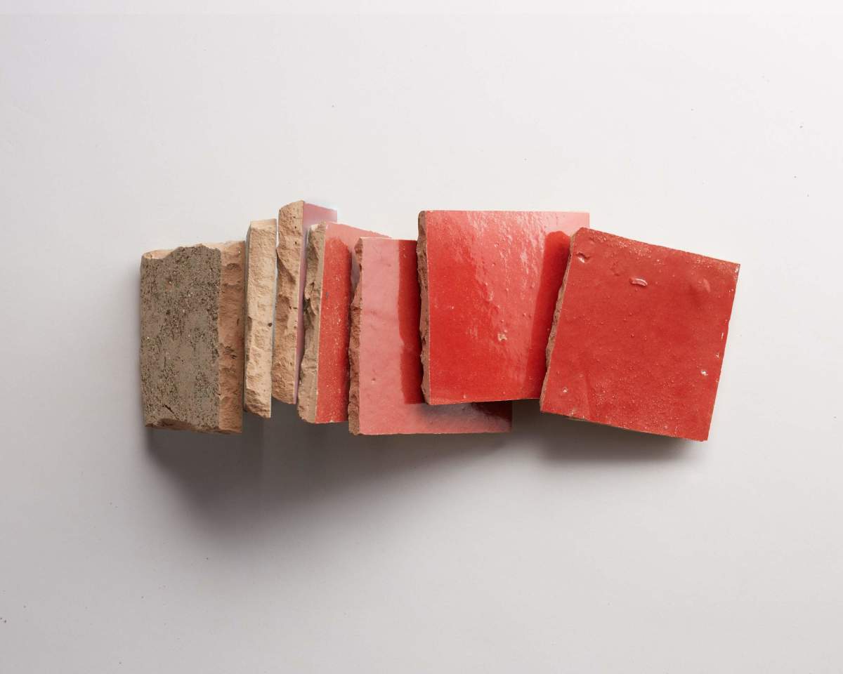 Seven red ceramic tiles of varying thicknesses are arranged in a staggered row on a white background.
