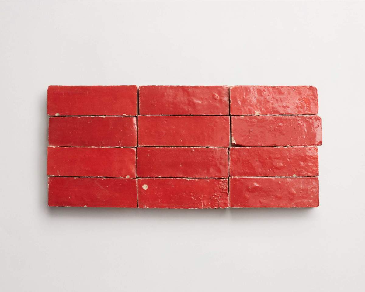 Twelve red rectangular bricks are arranged in a neat grid of three rows and four columns on a white surface.