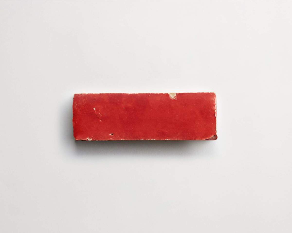 A single rectangular red brick with a slightly worn surface placed on a plain white background.