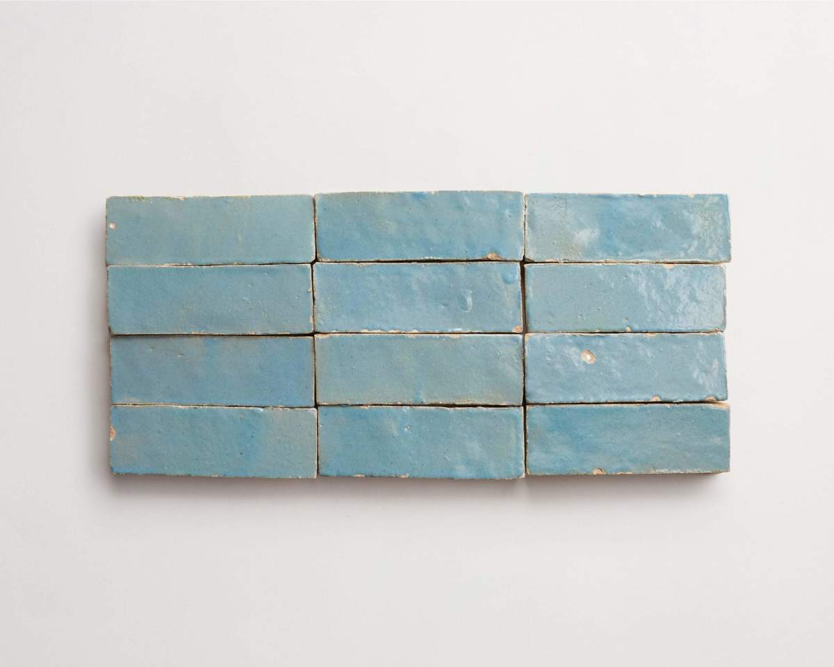 Twelve rectangular blue ceramic tiles are arranged in a grid of three rows and four columns on a white background.
