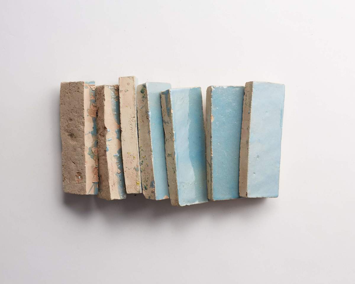 Seven rectangular pieces of material with rough beige edges and smooth light blue surfaces are arranged vertically on a white background.