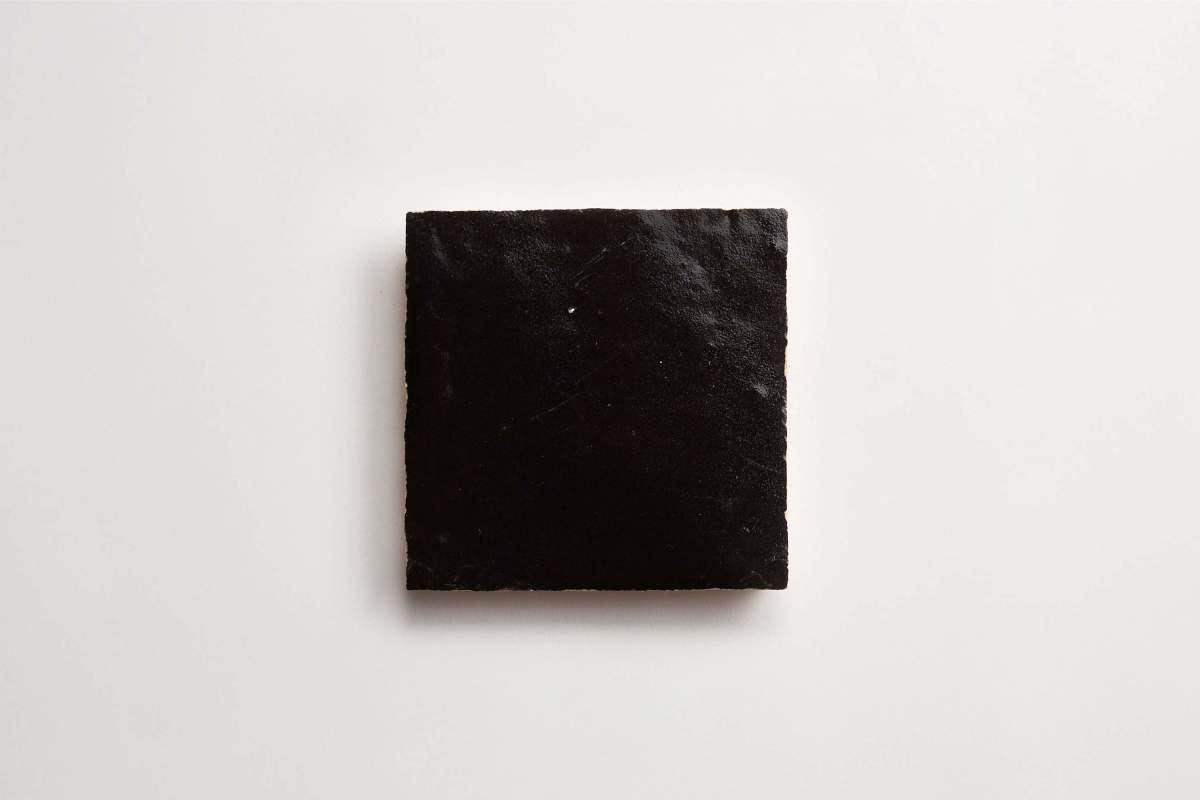 A single black square tile is placed on a plain white background.