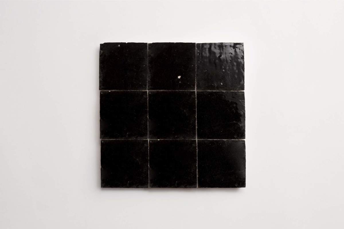 Nine glossy black square tiles are arranged in a 3x3 grid on a plain white background.