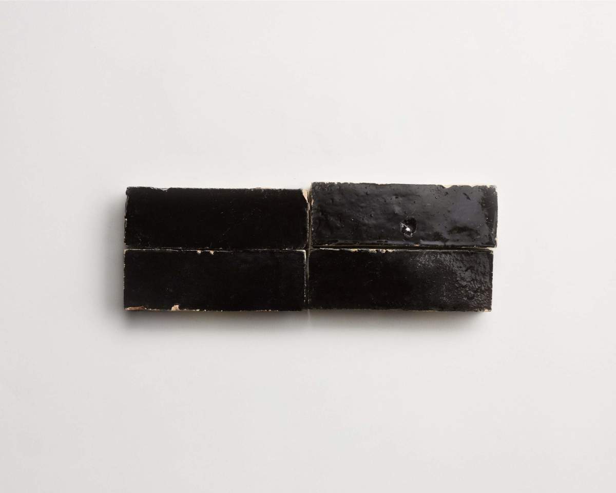 Four rectangular black licorice pieces are arranged in a horizontal row on a plain white background.