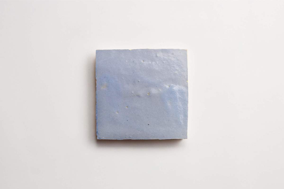 A single square blue ceramic tile on a plain white background.