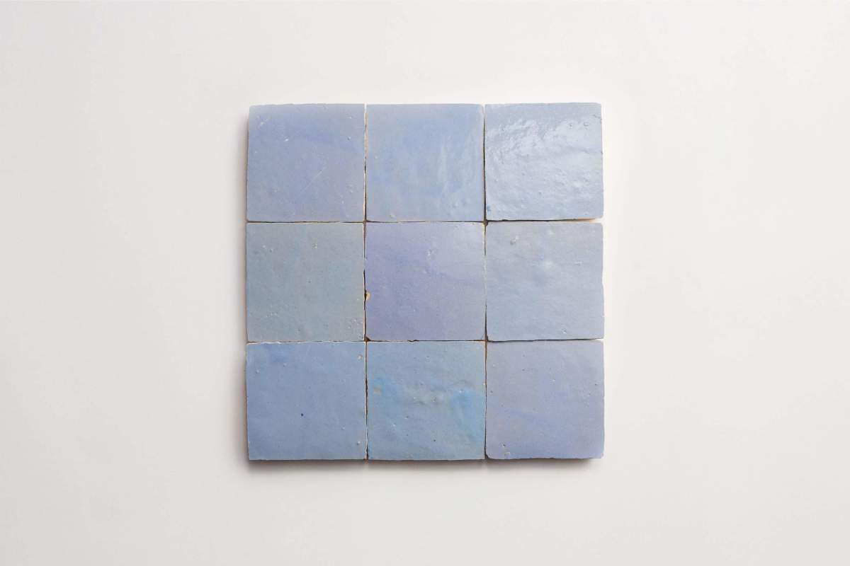 Nine square light blue ceramic tiles are arranged in a three-by-three grid on a plain white background.