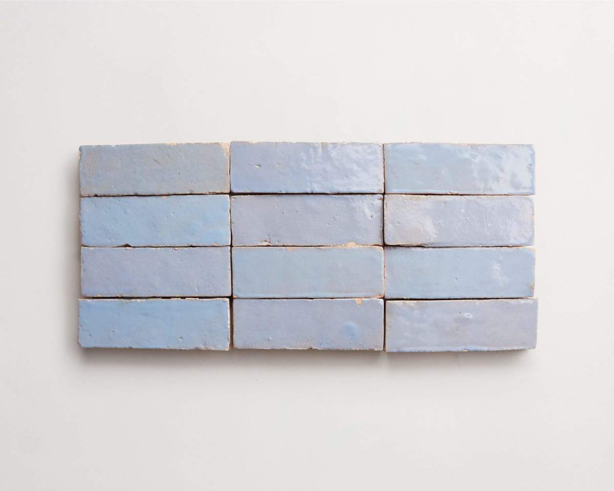 Twelve rectangular, light blue ceramic tiles are arranged in three rows of four on a plain white background.