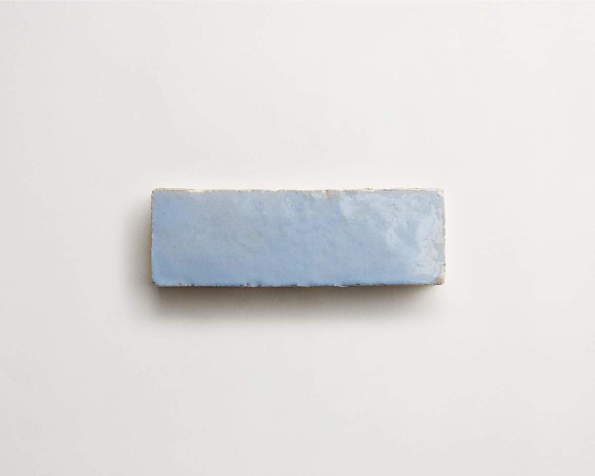 A single rectangular light blue tile with a slightly uneven, textured surface is shown against a white background.