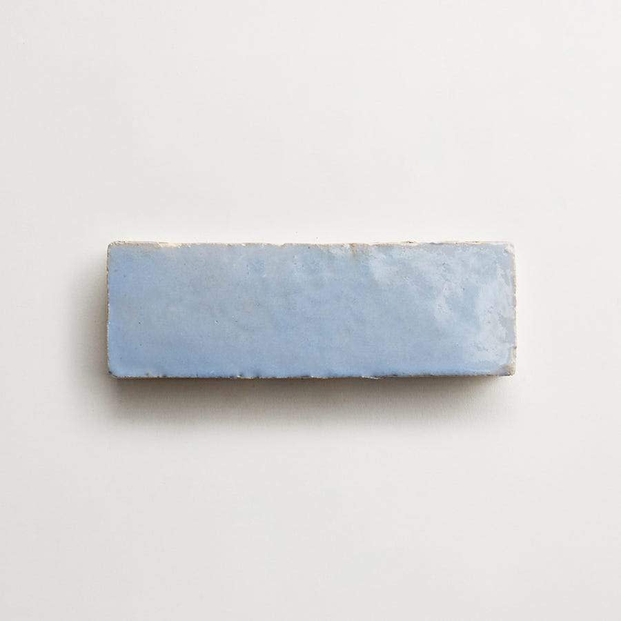 A rectangular, light blue ceramic tile with a glossy finish is placed on a plain white background.