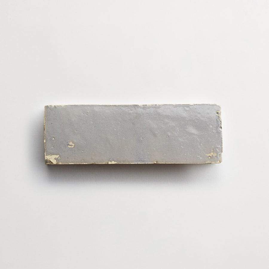 A rectangular bar of gray clay with rough edges shown on a plain white background.
