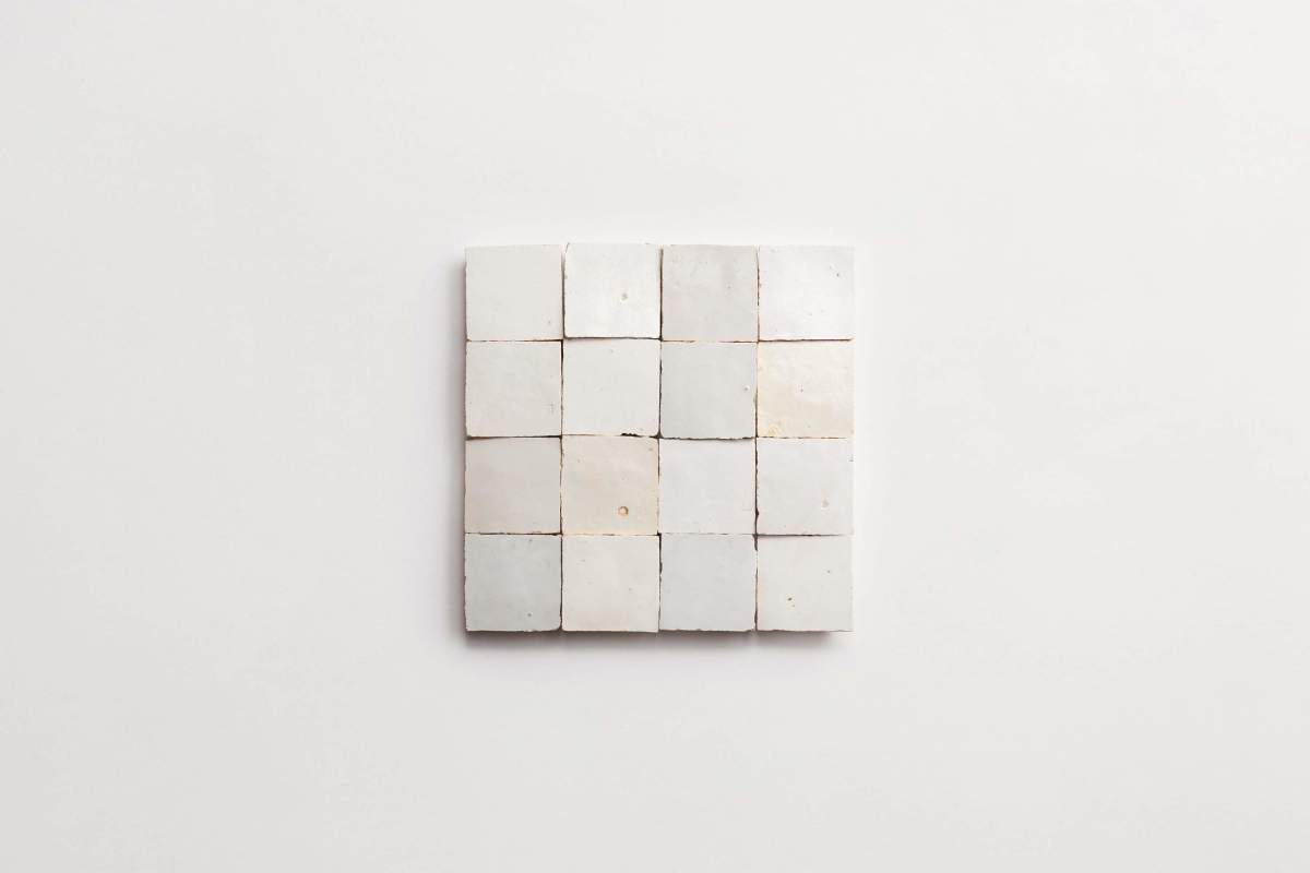 A square arrangement of sixteen white ceramic tiles is placed on a plain white background.