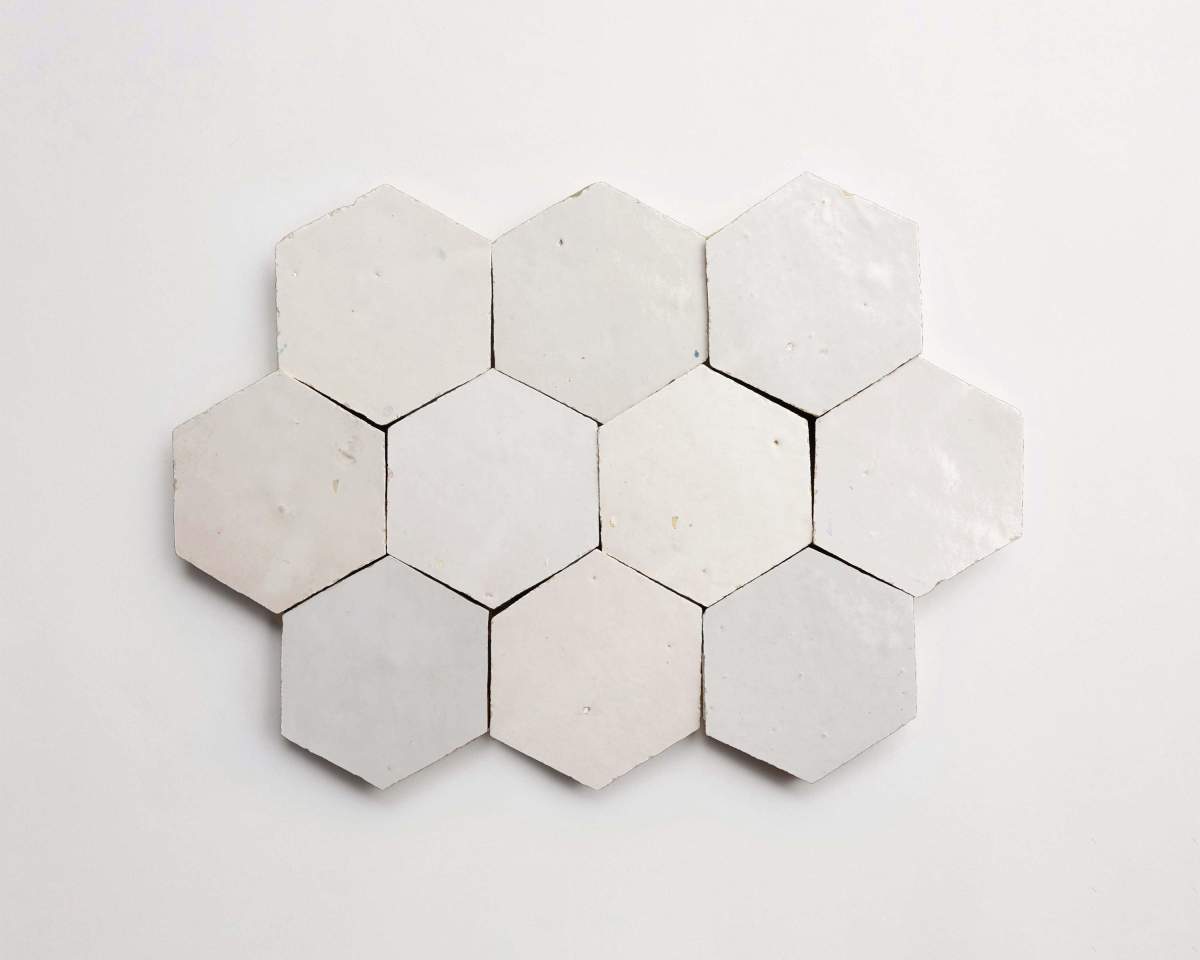 Twelve white hexagonal tiles are arranged in a honeycomb pattern on a plain white surface.