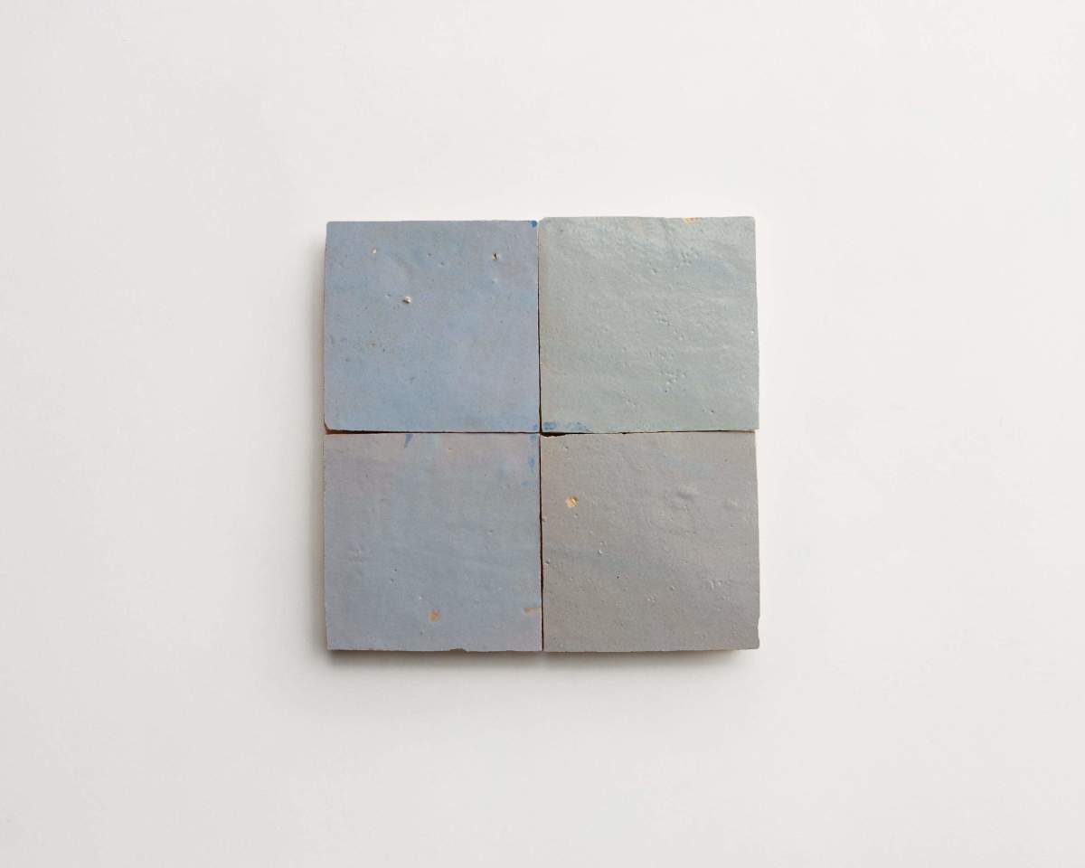 Four square, light blue-gray ceramic tiles arranged in a 2x2 grid on a plain white background.