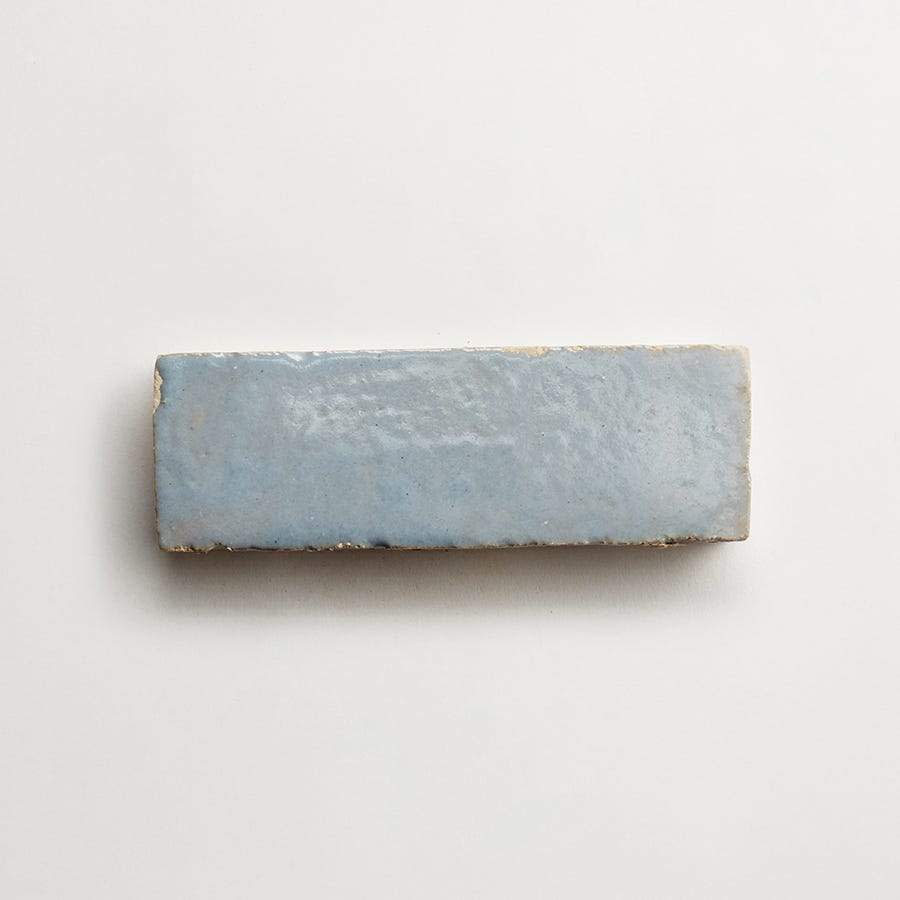 A rectangular, light blue ceramic tile with a glossy finish, photographed on a plain white background.