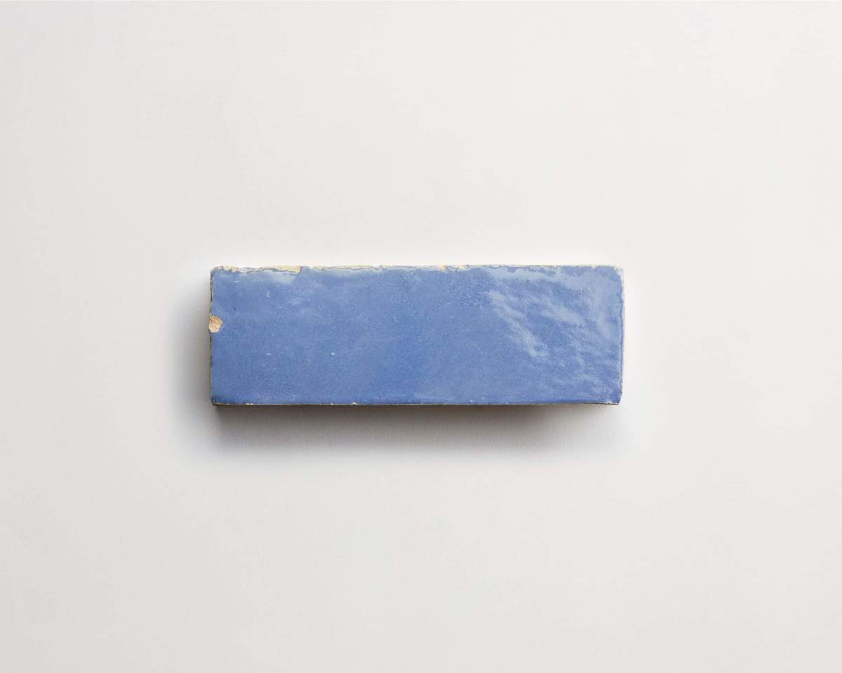 A rectangular blue ceramic tile with slightly chipped edges displayed on a plain white background.
