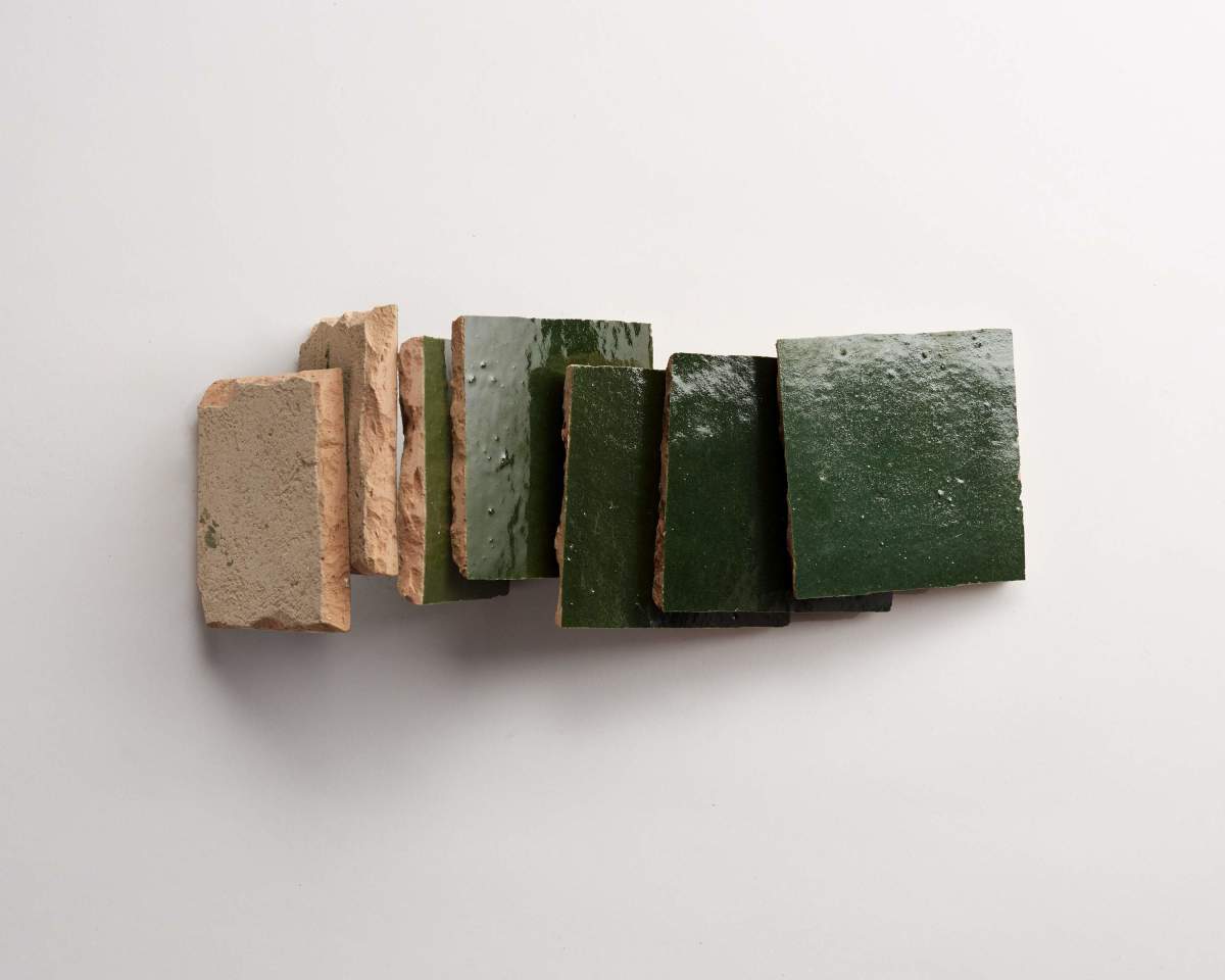 A row of rectangular tiles, some unglazed with a rough beige surface and others glazed with a glossy green finish, arranged side by side on a white background.