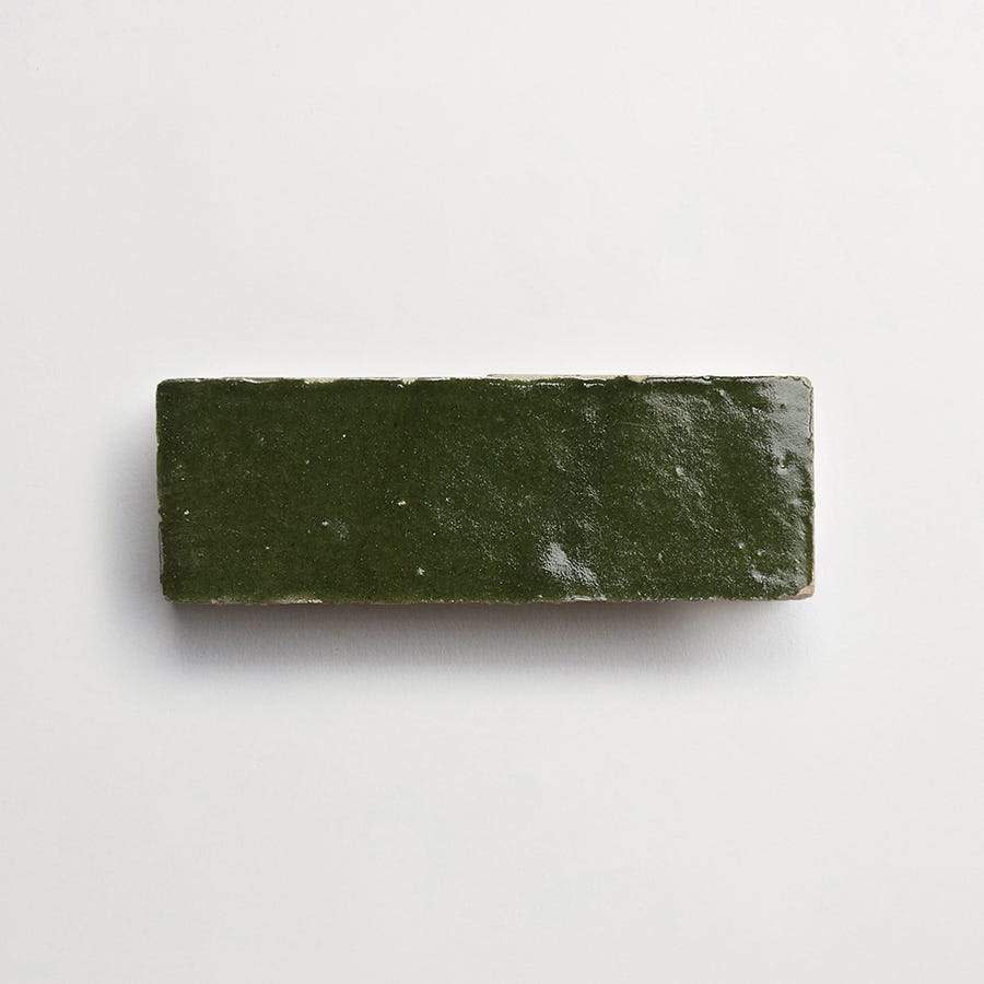 A rectangular, dark green ceramic tile with a glossy finish, placed on a plain white background.