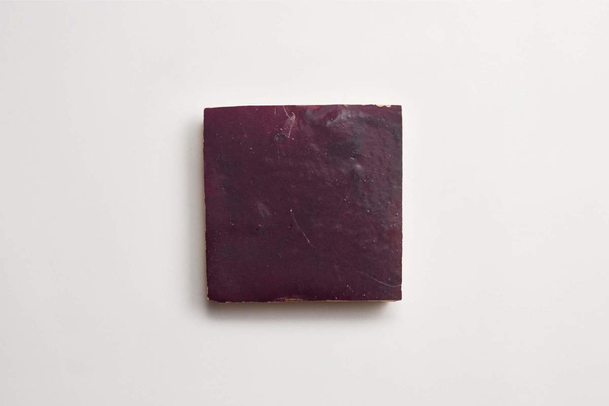 A single, square, dark purple tile is centered on a plain white background.