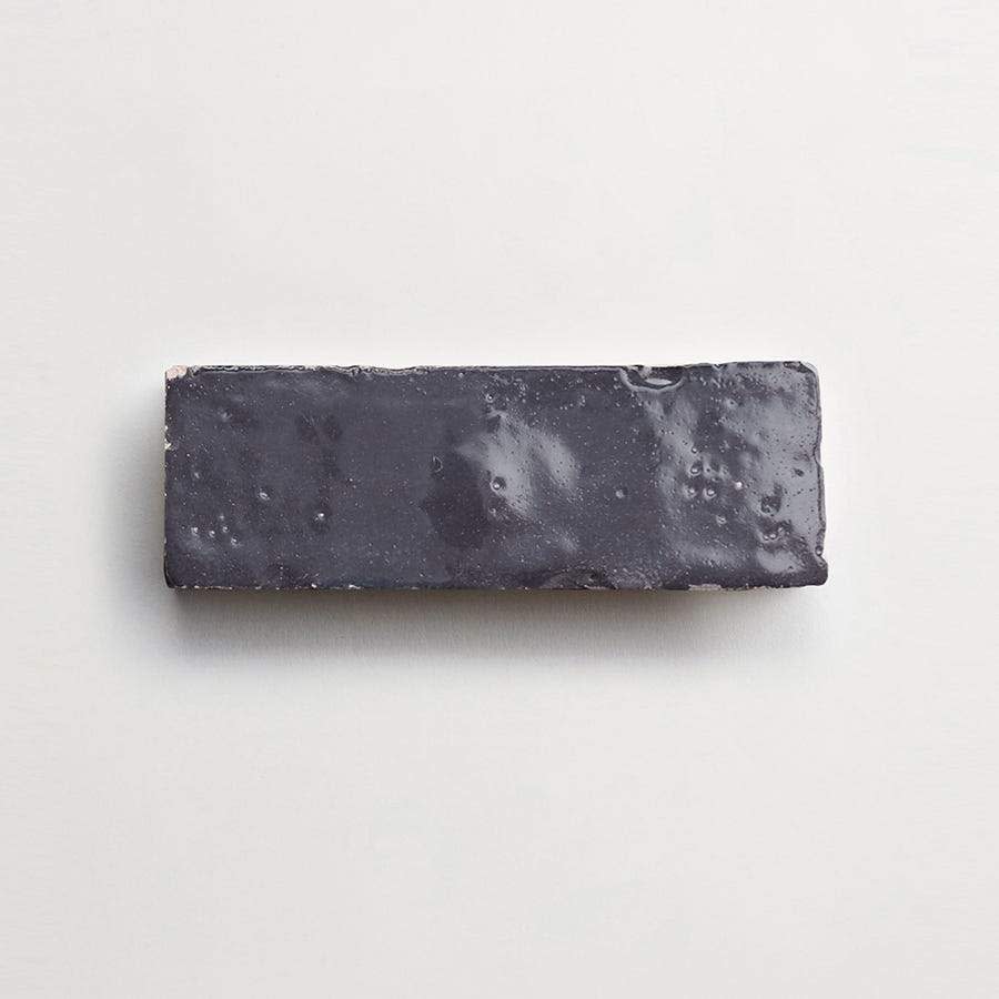 A rectangular, dark-colored bar with a glossy surface, placed on a light, plain background.