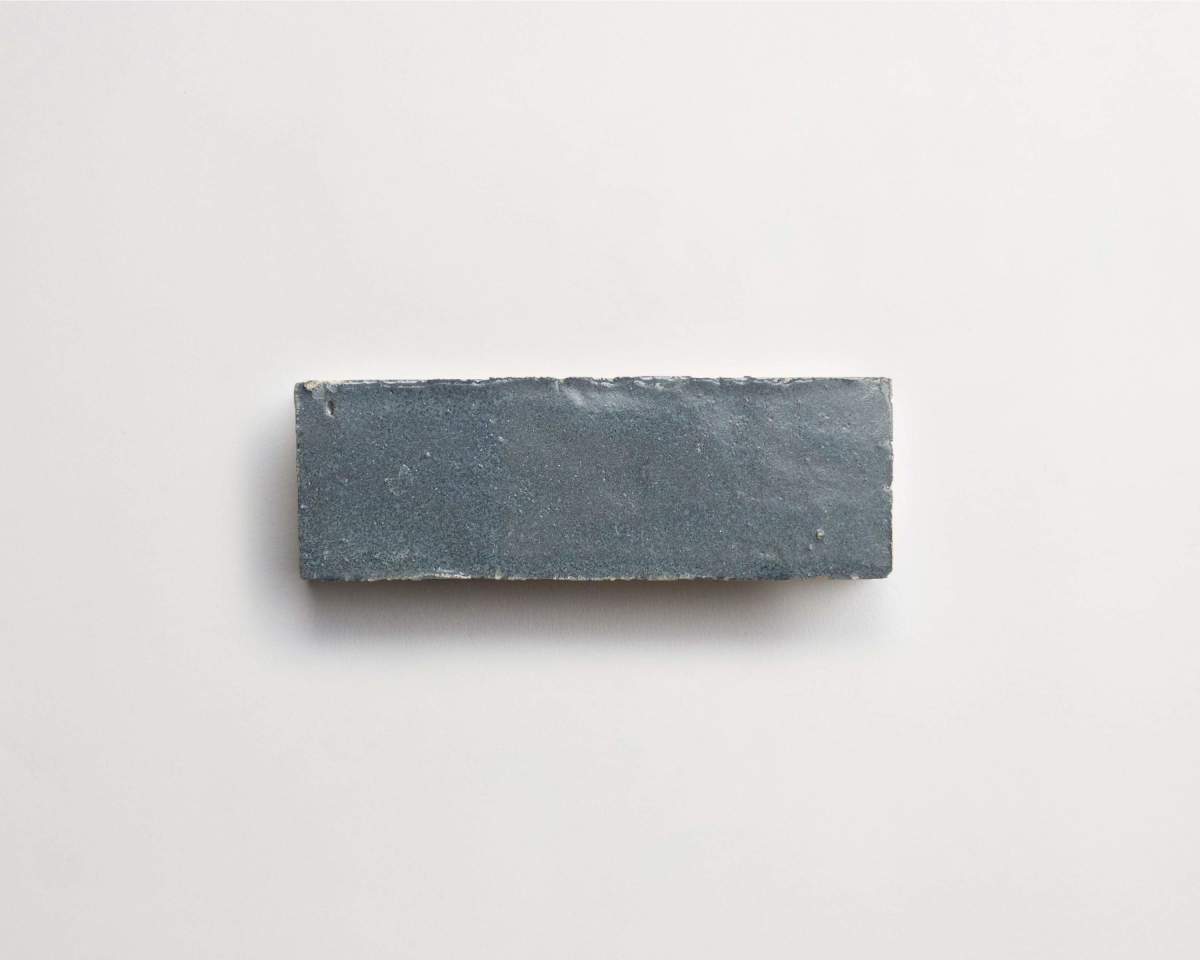A single rectangular gray brick with a rough texture is placed on a plain white background.
