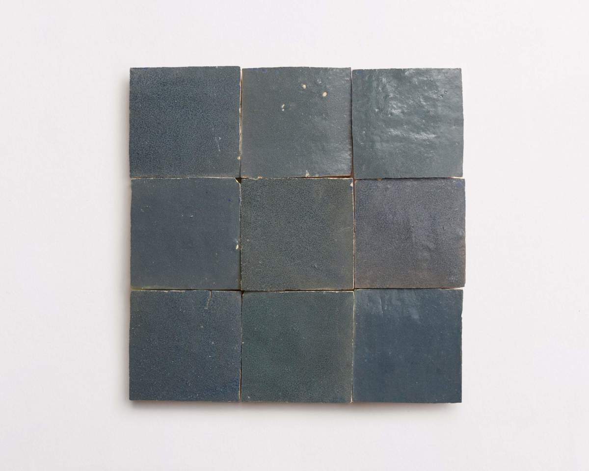 Nine dark blue square ceramic tiles arranged in a 3x3 grid on a plain light-colored background.