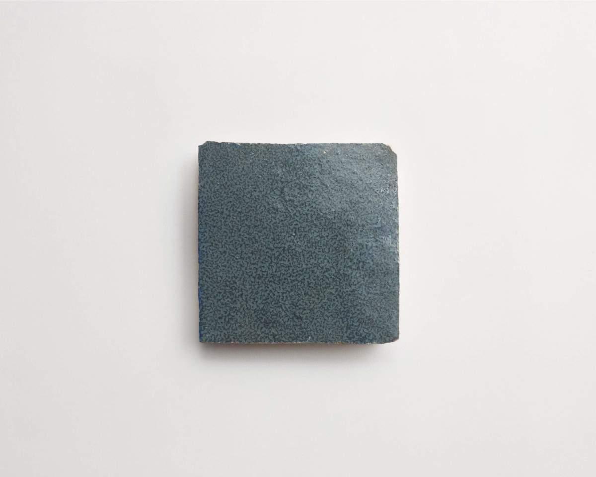 A single square dark blue ceramic tile with a textured surface placed on a plain white background.