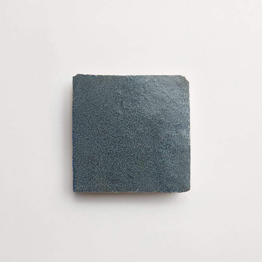 A single square, dark blue ceramic tile with a textured surface is centered on a plain white background.