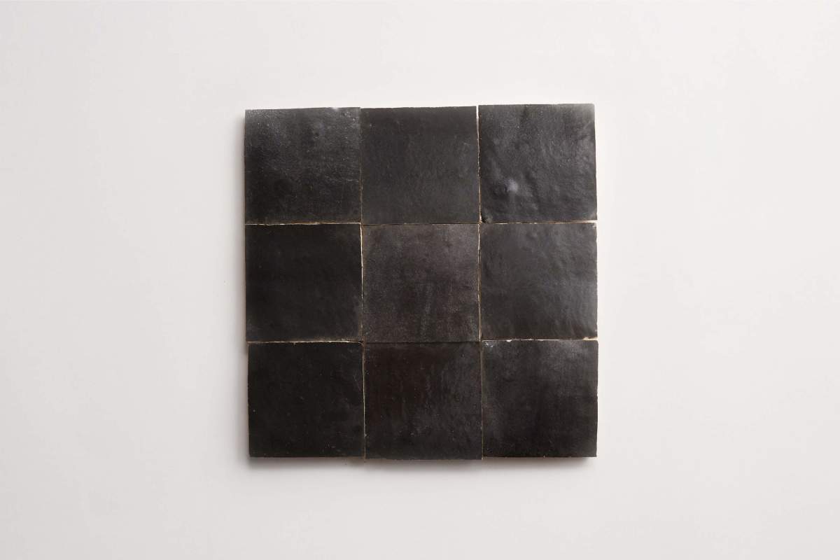 Nine square black tiles are arranged in a three-by-three grid on a plain white background.