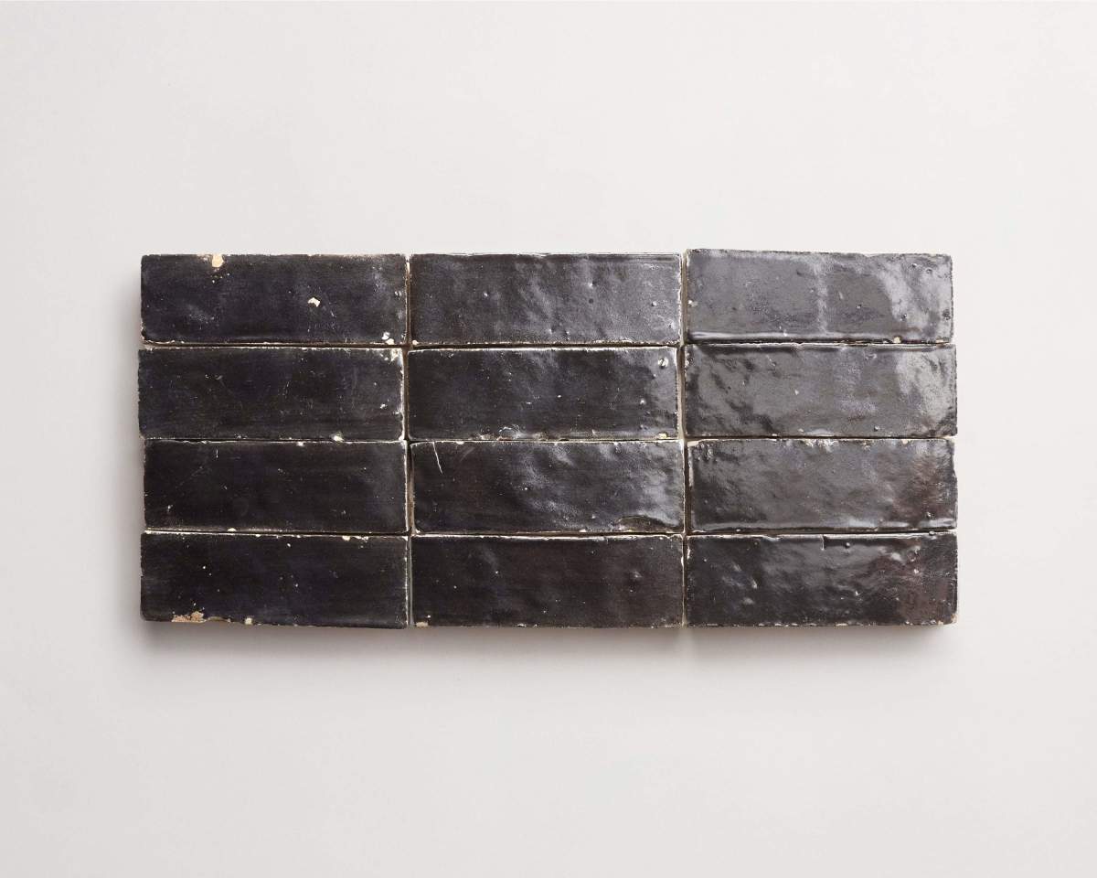 Twelve rectangular black ceramic tiles are arranged in a horizontal grid of three rows and four columns on a plain white background.
