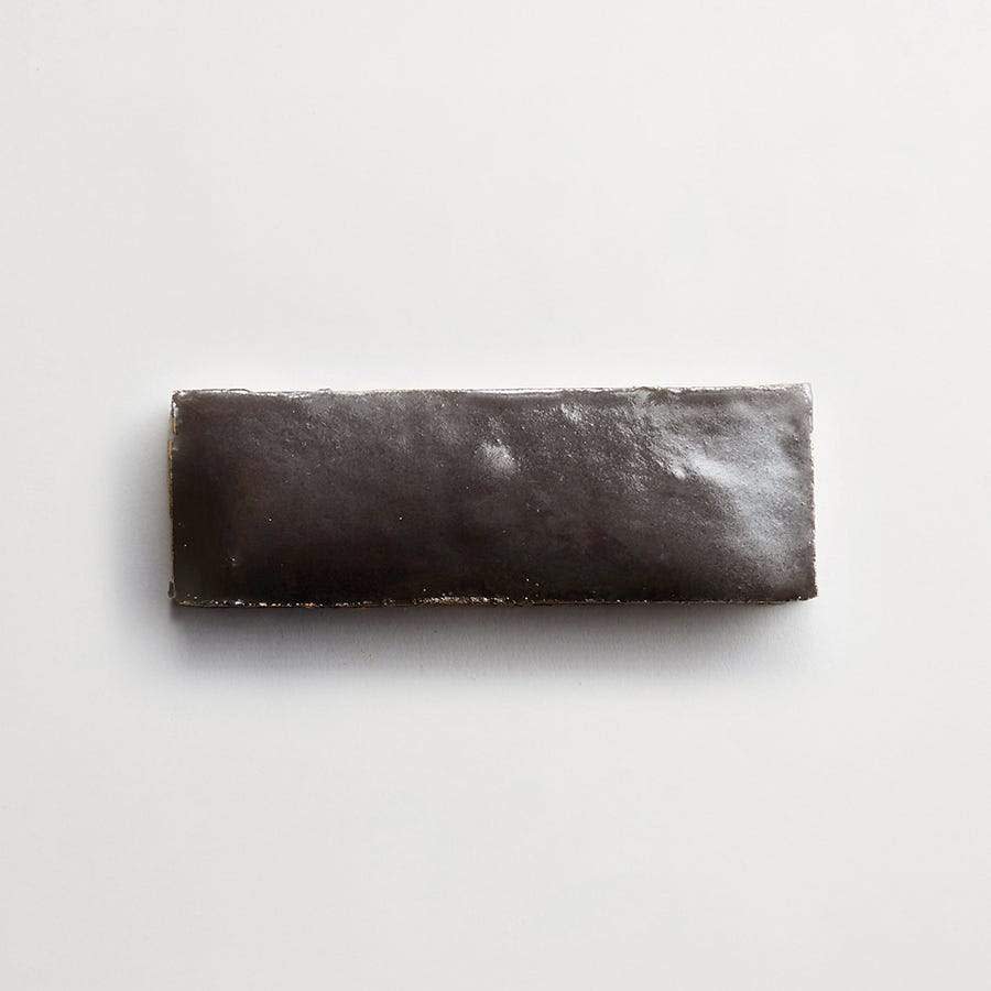 A rectangular, glossy, dark brown bar rests on a plain white surface.
