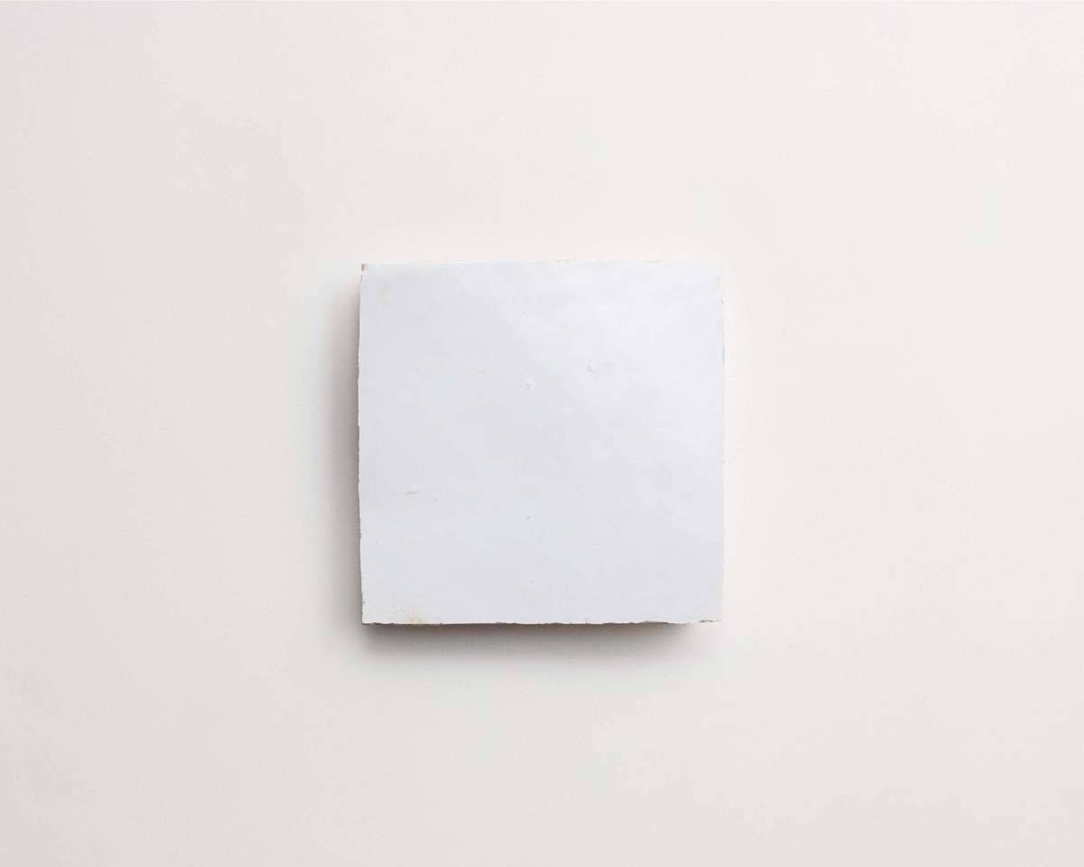 A square piece of white paper or card is centered on a plain, light-colored background.