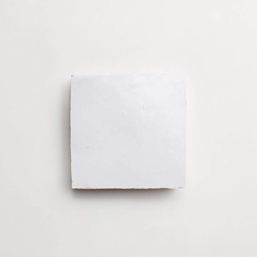 A plain white ceramic tile with rough edges is centered on a white background.
