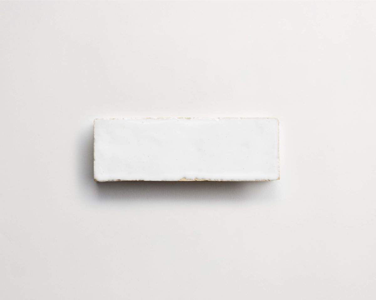 A rectangular white ceramic tile placed on a light, neutral background.