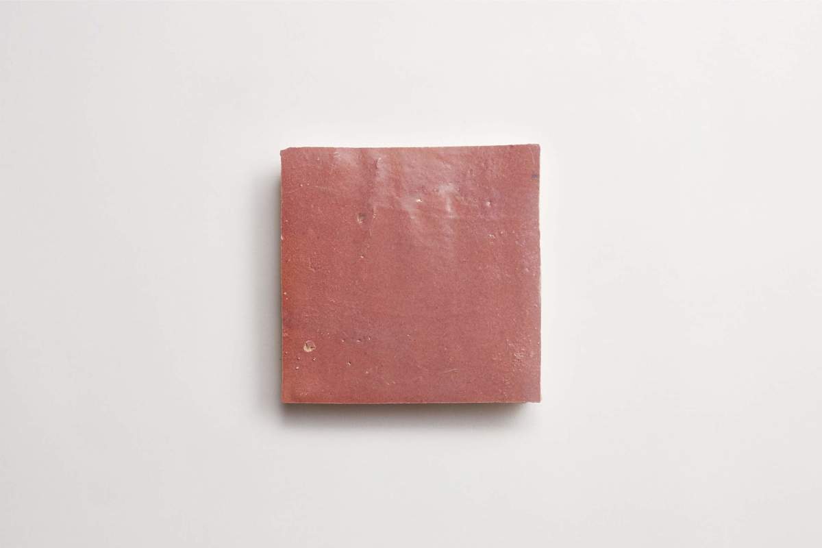 A single square, reddish-brown tile is centered on a plain white background.