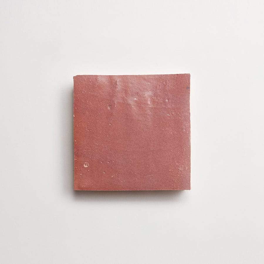 A single square pink ceramic tile with a matte finish, centered on a plain white background.