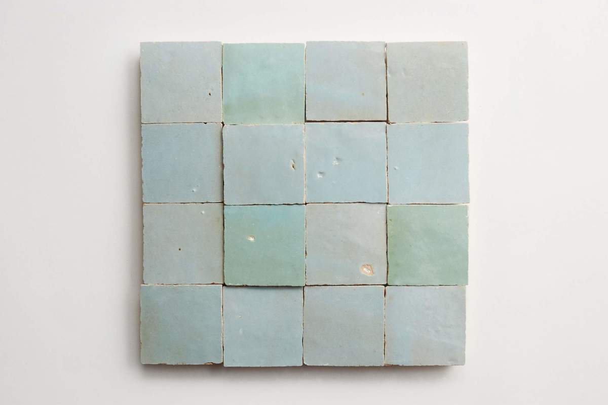 A square arrangement of sixteen blue-green ceramic tiles with slight variations in color and surface texture, laid out on a white background.